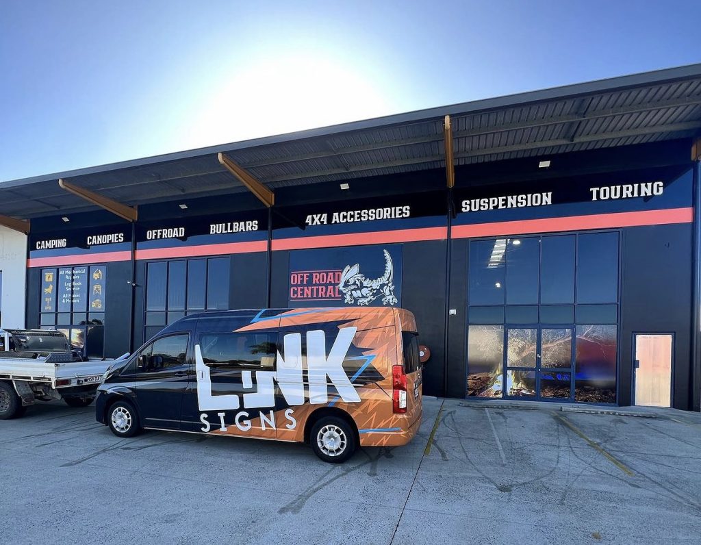 Link signs vehicle wrapped in livery in front of large building